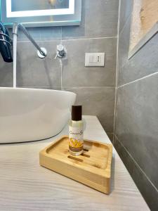 a bottle of essential oil on a wooden tray in a bathroom at Il Telescopio in Noto