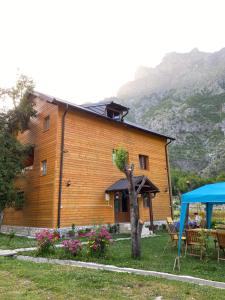 Casa de madera con mesa y tienda azul en Guesthouse Mehmeti, en Valbonë