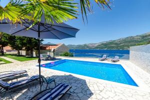 a swimming pool with chairs and an umbrella next to a pool at Villa Gabriela in Korčula