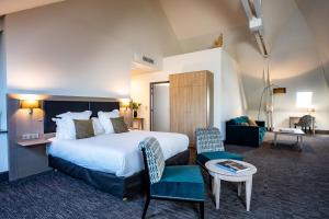 a hotel room with a large bed and a living room at Hôtel Spa Marotte in Amiens
