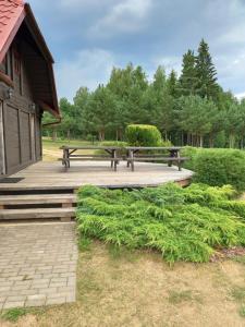 einem Picknicktisch und einer Bank auf einer Holzterrasse in der Unterkunft Brīvdienu māja Greiži in Dzirciems