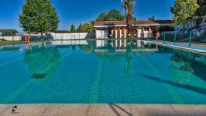 a swimming pool with blue water in front of a house at POSADA EL ARRIERO in Torrejón el Rubio