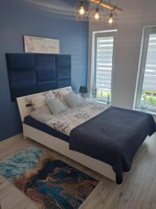 a bedroom with a large bed with a blue wall at Aqua Blue Apartament in Reda