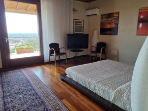 um quarto com uma cama, uma televisão e uma janela em B&B Belvedere em Castiglione delle Stiviere