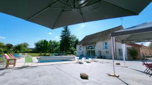 a patio with an umbrella and chairs and a pool at Domaine Ravy-Lilas in Saint-Symphorien-sur-Saône