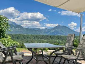 a table and chairs on a deck with mountains in the background at Apartma AS in Bled
