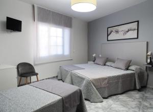 1 dormitorio con 2 camas, silla y ventana en Hotel Florida Mar, en Sanxenxo