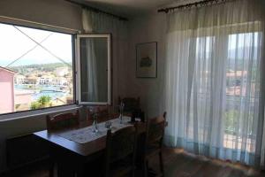 a dining room with a table and a large window at Apartman Nađa in Vrboska