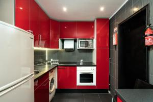 a red kitchen with red cabinets and a refrigerator at Casa Pescador in Carvoeiro