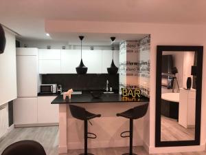 uma cozinha com um balcão e bancos num quarto em Black and White Suitte "Plaza" em Noja