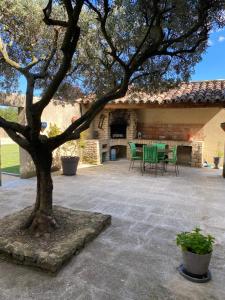 une terrasse avec un arbre, une table et des chaises dans l'établissement Villa dans le LUBERON à 2 km de LOURMARIN, à Lauris