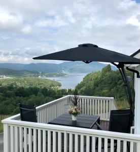 een tafel met een zwarte parasol op een balkon bij Fjord road in Hjelmeland