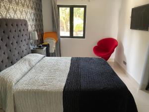 - une chambre avec un lit et une chaise rouge dans l'établissement Sun club playa del águila by la piedra viva, à San Bartolomé