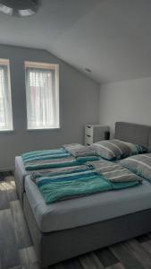 twee bedden in een kamer met witte muren en ramen bij Ferienwohnung Krabbe im Haus-Neuharlingersiel in Neuharlingersiel