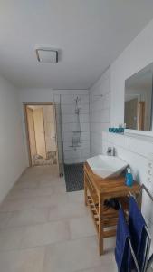 een witte badkamer met een wastafel en een douche bij Ferienwohnung Krabbe im Haus-Neuharlingersiel in Neuharlingersiel