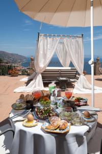 einen Tisch mit Teller mit Lebensmitteln auf dem Dach in der Unterkunft Isoco Guest House in Taormina