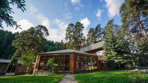 a wooden house with glass windows in the grass at Energetik Hotel in Arkhyz