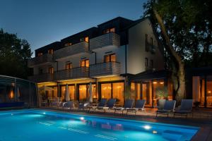 a house with a swimming pool in front of a building at M2 Resort Wellness & Spa in Ostrowo