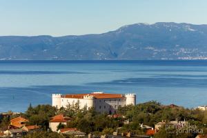 a building on a hill next to a body of water at Kvarner View Rooms in Kraljevica