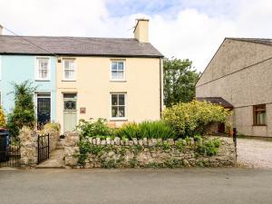 a white house with a stone fence and flowers at Silva in Penmon
