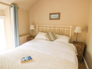 a bedroom with a white bed with a book on it at Silva in Penmon