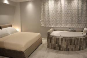 a bedroom with a bed and a bath tub next to a bed sqor at 360° View Suites Tan in Neapoli Voion