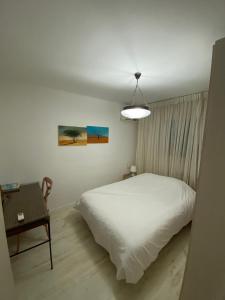 a bedroom with a white bed and a table at צימר דירת בכור in Yavneʼel