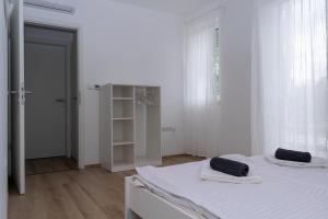 a white room with two beds and a closet at Zamárdi Árnyas Apartman in Zamárdi