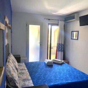 een slaapkamer met een bed met blauwe lakens en een raam bij B&B Su Tostainu in Teulada