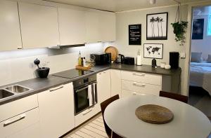 una cocina con armarios blancos y una mesa y una habitación en Two bedroom apartment near the city centre. en Tromsø