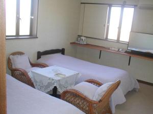 a room with two beds and a table and chairs at ビジネスホテル六号 in Omitama