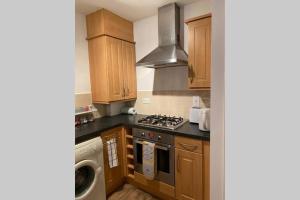 a kitchen with wooden cabinets and a stove top oven at Modern stylish flat over garage in Crewe