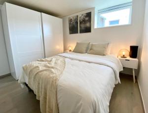 1 dormitorio con cama blanca y ventana en Two bedroom apartment near the city centre., en Tromsø