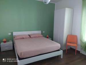 1 dormitorio con 1 cama y 1 silla naranja en Il Peperoncino, en San Vito lo Capo