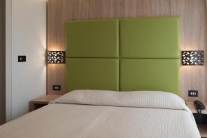 a bedroom with a white bed with a green headboard at Hotel St Gregory Park in Rimini