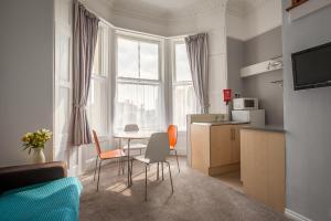 a living room with a table and chairs and a kitchen at Clydesdale Apartments in Torquay