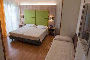 a bedroom with a bed with a green headboard at Hotel St Gregory Park in Rimini