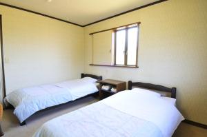 Duas camas num quarto com um espelho e uma janela em ビジネスホテル六号 em Omitama