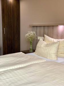 a bed with white sheets and a vase of flowers at Stefans Gästezimmer in Kirchhatten +29 photos