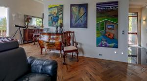 a living room with a table and paintings on the wall at ICELAND SJF Villa, Hot tub & Outdoor Sauna Amazing Mountains and City View Over Reykjavík in Reykjavík