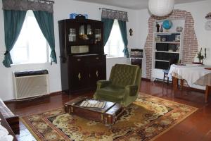 a living room with a green chair and a table at Guest house and Cuisine by Meri Poppins in Dedoplis Tskaro