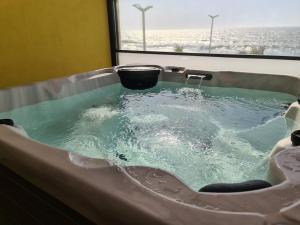 uma banheira de hidromassagem na casa de banho com uma janela em GOLD SUITE T2-PRAIA DO FURADOURO em Ovar