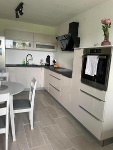 eine Küche mit weißen Schränken und einem Tisch mit Stühlen in der Unterkunft Apartment Tomy in Rijeka