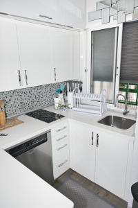 una cucina con armadi bianchi e lavandino di Malibu 2 apartamento con aire acondicionado, campo de tennis y piscina con solarium a Puerto Rico de Gran Canaria