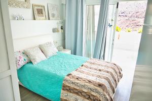una camera da letto con un letto con tende blu e una finestra di Malibu 2 apartamento con aire acondicionado, campo de tennis y piscina con solarium a Puerto Rico de Gran Canaria
