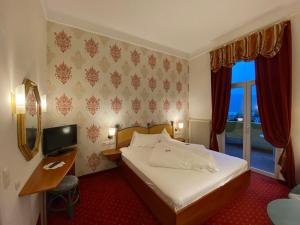 a hotel room with a bed and a desk and a window at Hotel Kaiser Franz Josef in Millstatt