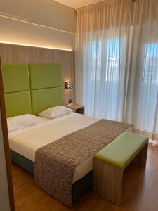 a bedroom with a large bed with a green headboard at Hotel St Gregory Park in Rimini