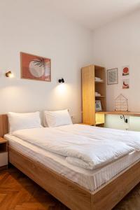 1 dormitorio con 1 cama grande con sábanas blancas en Check-in Apartments en Leópolis