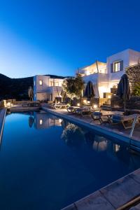 Nesea Sifnos - Luxury Residences في بلاتيس ييالوس سيفنوس: مسبح وكراسي ومظلات بجانب مبنى