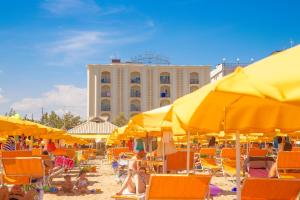 una spiaggia con sedie e ombrelloni e un edificio di Hotel San Giorgio a Cesenatico